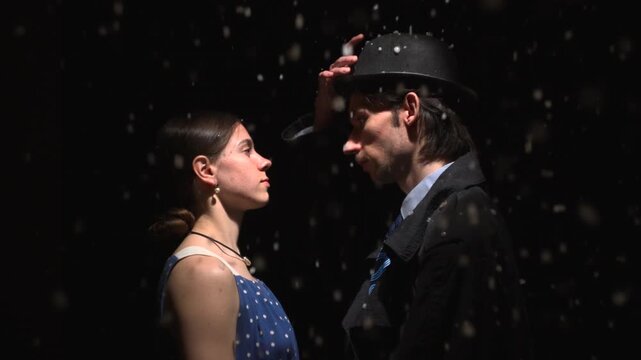Man tipping his hat toward a woman in falling snow