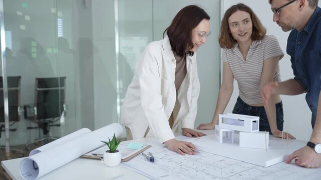 Architects and urban planners are working together, analyzing building plans and creating a small scale architectural model for a new residential or commercial project