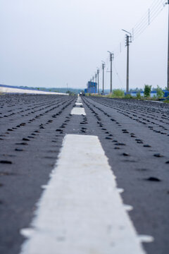 Mukutmanipur Dam Close up of black asphalt surface with road studs and lane markings.
