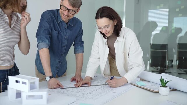 Group of architects discussing building blueprints and a structural model, collaborating on an urban development project in a modern office environment. Architects at work