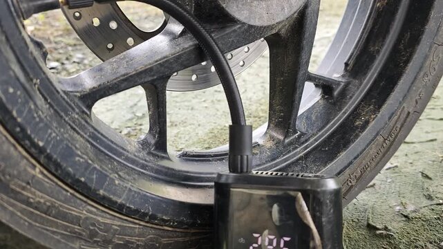 Motorcycle tires being inflated using an electric pump, close up