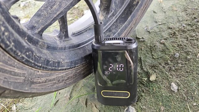 Motorcycle tires being inflated using an electric pump, close up