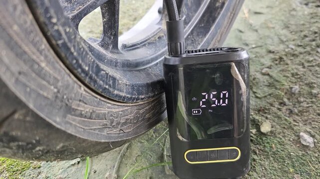 Motorcycle tires being inflated using an electric pump, close up