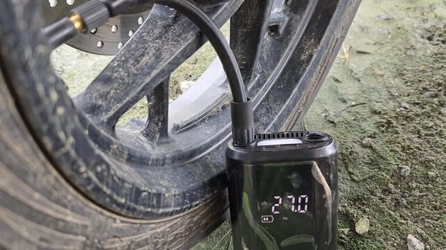 Motorcycle tires being inflated using an electric pump, close up