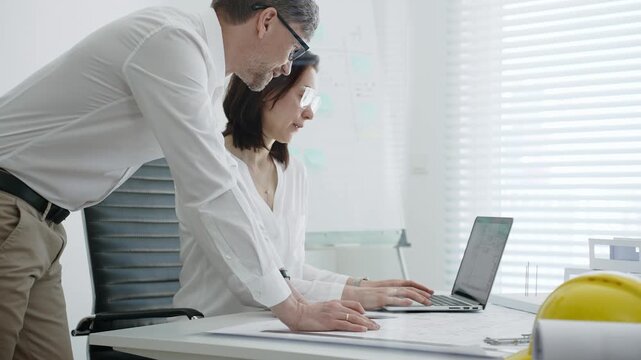 Architects collaborating on building design, reviewing blueprint plans and architectural models, creating detailed floor layout sketches in a professional office environment