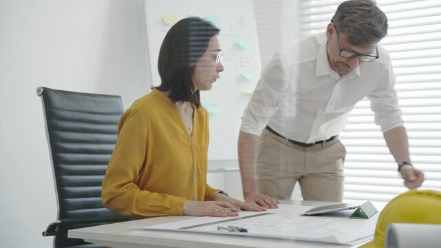 Architects and construction planners collaborating over blueprints and digital plans, using tablets, tools and whiteboard to draft and review building designs in a modern office setting