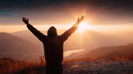 Fototapeta premium Man with outstretched arms embracing the sunrise over a majestic mountain landscape, symbolizing hope and achievement.