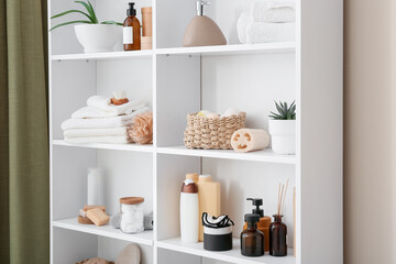 White bathroom shelf with skincare products, towels, and natural spa accessories for home...