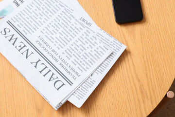 Fototapeta premium Daily news newspaper and smartphone on wooden table, information consumption and digital media