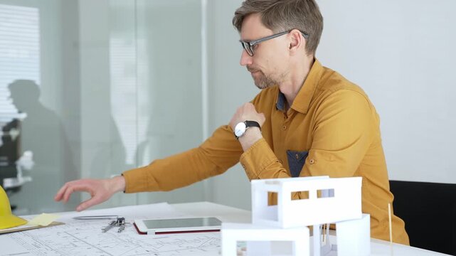 Professional architect designing a new building project, planning with blueprints and a scale model in a modern office, developing urban structures and innovative construction ideas