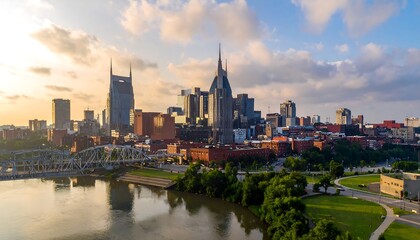 Obraz premium A city skyline with a river flowing through it, surrounded by lush greenery and a vibrant blue sky with clouds