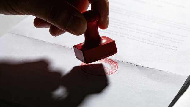 Hand stamping document with red ink, approval concept