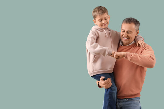 Elderly man and his little grandson bumping fists on color background. National Grandpa Day