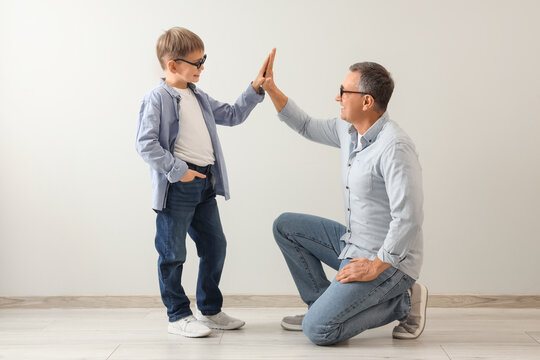 Elderly man and his little grandson giving high-five to each other on white background. National Grandpa Day