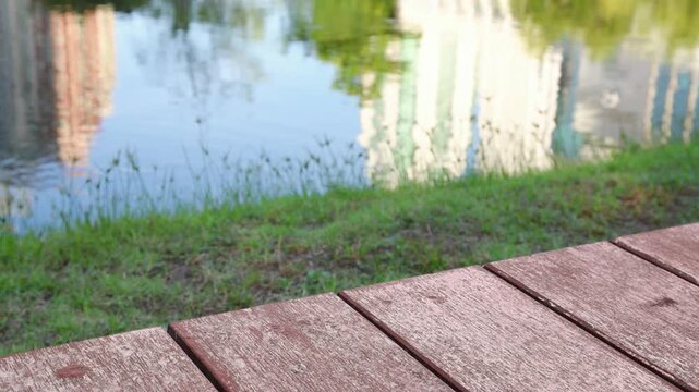wooden patio by lakeside with highrise reflection, relaxing corner in public park