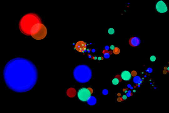 Abstract composition featuring oversized blue and orange bokeh circles with a colorful light trail against a black background.