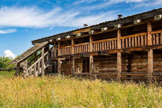 The impressive wooden walls of a reconstructed Old Slavic fortress, made of round, hewn logs. Old barracks and boyar chambers. A bright, sunny day.