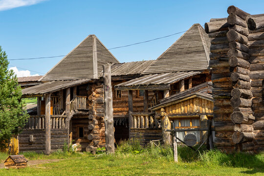 The impressive wooden walls of a reconstructed Old Slavic fortress, made of round, hewn logs. Old barracks and boyar chambers. A bright, sunny day.