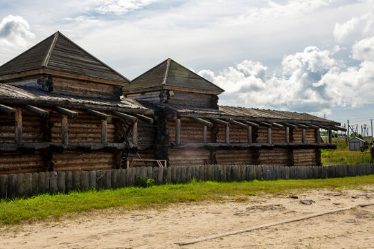 The impressive wooden walls of a reconstructed Old Slavic fortress, made of round, hewn logs. Old barracks and boyar chambers. A bright, sunny day.
