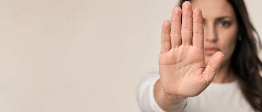 Young woman making a stop gesture with her hand, showing refusal or disagreement.