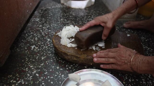 Close up of an Indian woman crushing fresh radish on a traditional sil batta stone grinder during food preparation. Video footage capturing traditional cooking and daily life in India.