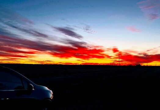 An electric red sunset gleams over Montana fields