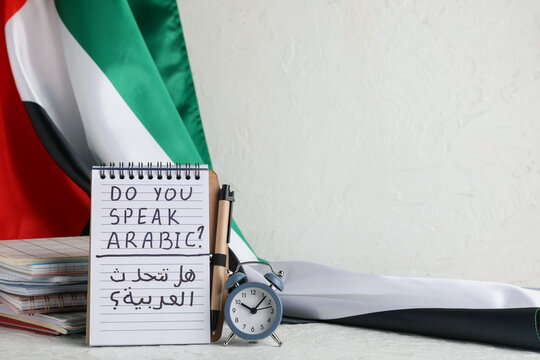 Arabic language learning with notebook, pen, alarm clock, and UAE flag for education and cultural exchange