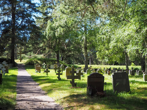 Skogskyrkog&aring;rden forest cemetery surrounded by lush green trees on a sunny summer day in Stockholm Sweden