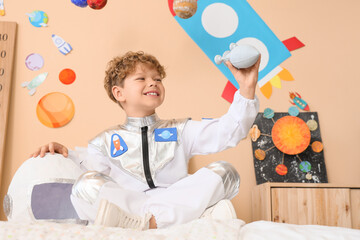 Smiling young boy in astronaut costume playing with toy rocket, space exploration and childhood imagination © Pixel-Shot