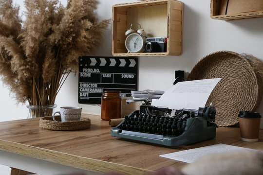Vintage typewriter with screenplay and film production accessories on wooden desk creative writing and filmmaking, a screenplay is loaded into the typewriter surrounded by film production accessories