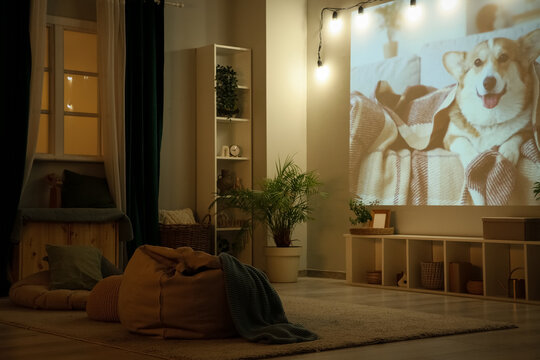 Cozy home cinema setup with projector displaying happy corgi dog on blanket, relaxing evening entertainment