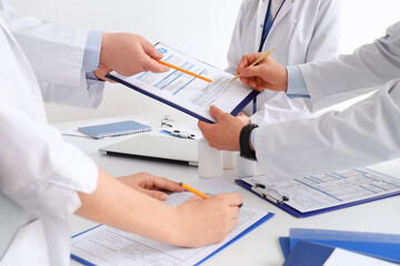 Medical professionals collaborating on patient records, healthcare team reviewing documents, doctors discussing treatment plans, hospital administration paperwork