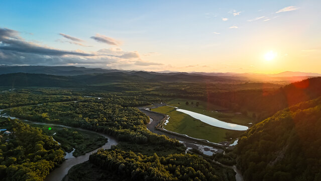 Aerial sunset over a winding river and forested hills