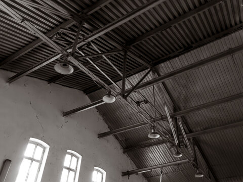 Black and white interior of abandoned factory with metal roof trusses