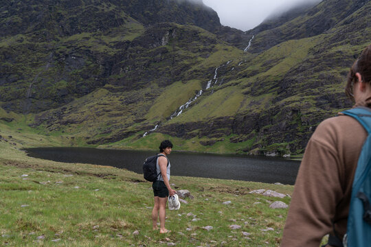 Hikers approaching lake with waterfalls in mountains