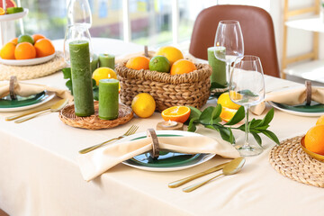 Obraz premium Beautiful table setting with citrus fruits and burning candles in living room
