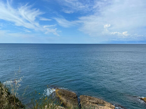Blue sea sky and coastal rocks overgrown wild herbs