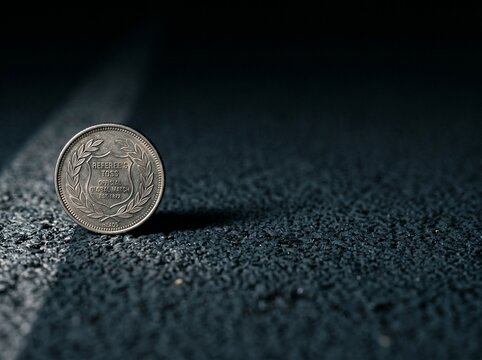A referees toss coin standing upright on a dark textured sports field