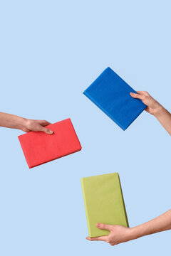 Hands holding books on light blue background