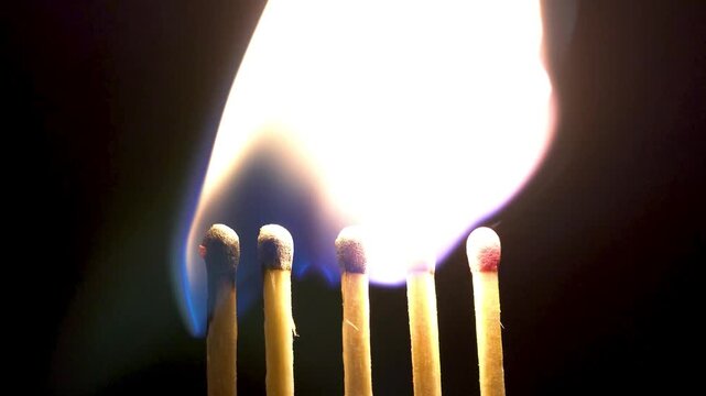 Matches being lit on a black background, close up view