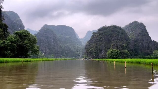 Peaceful view of the Ngo Dong River winding through the limestone karst countryside of Tam Coc, Ninh Binh, Vietnam.