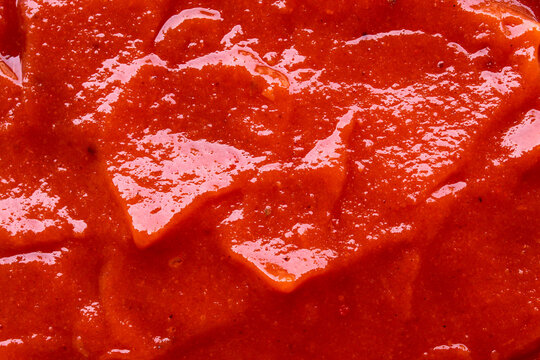 the detailed texture of tomato sauce or chili sauce which is bright red, thick, and has a natural shine