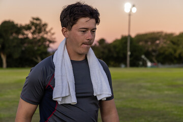 White towel is resting over dark athletic shirt on grassy sports field at dusk, floodlights glowing © wavebreak3