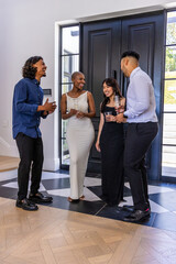 Naklejka premium Diverse friends wearing formal attire standing near black front door holding champagne flutes