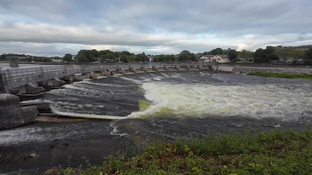 Cinematic flowing river footage showcasing Galway iconic Salmon Weir bridge, powerful water movement, historic architecture, nature, tourism and vibrant city atmosphere, Ireland