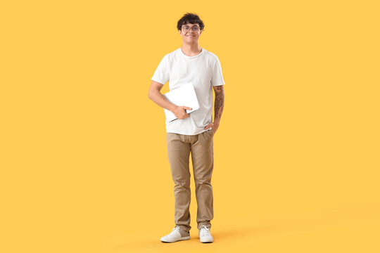 Male programmer with laptop on yellow background