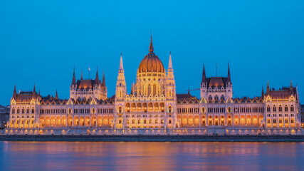 Fototapeta premium Stunning view of illuminated Hungarian Parliament Building reflecting in the Danube River at dusk