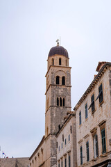 Obraz premium Dubrovnik old town, the catholic church and the cross, the bell tower, the clock tower, cobbled stone street, laneway and alleys and the city wall on a beautiful clear sky and blue Adriatic sea 