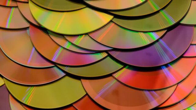 Reflection of the surface of a DVD discs, multiple optical discs stacked on top of each other like fish scales, colorful lines on the surface are caused by thin-film interference and diffraction