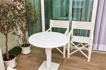 Fototapeta premium Modern balcony furniture set with white table and chairs, outdoor living space design, apartment patio decor
